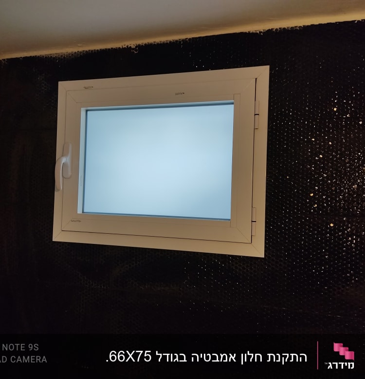 חלון אלומיניום עם מסגרת לבנה על קיר שחור